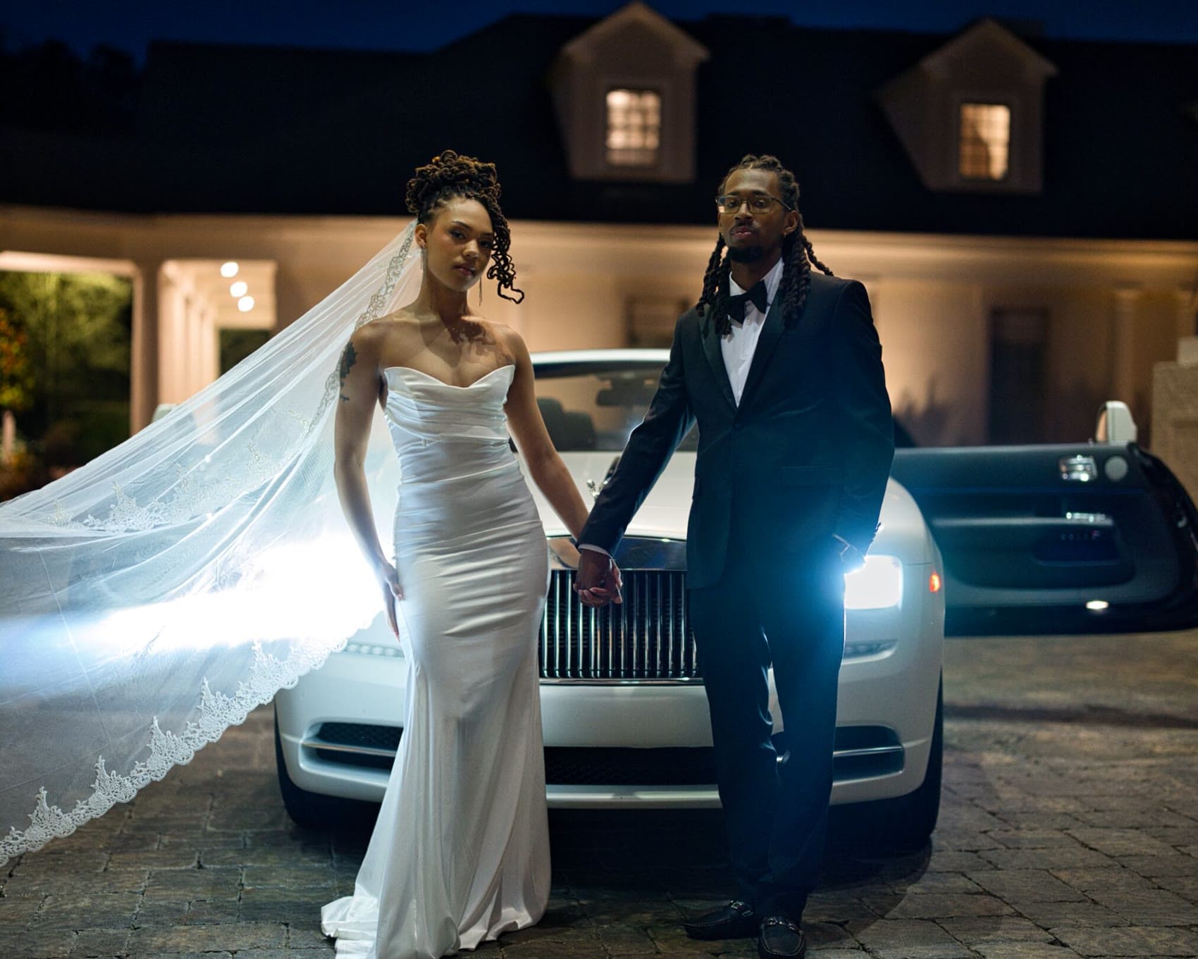 Bride and groom before a Rolls-Royce at night